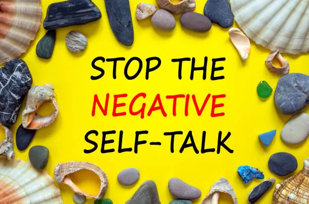 Stop negative self-talk symbol. Concept words Stop the negative self-talk on a beautiful yellow background. Sea stones and seashells. Psychological and stop negative self-talk concept. Copy space.