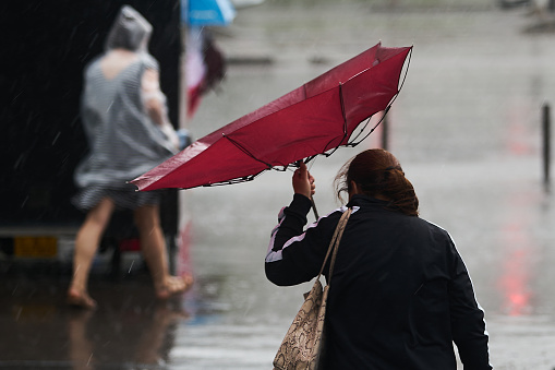 Bucharest, Romania - June 17, 2022: People cross the street during heavy rain.