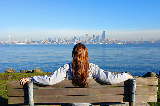 Woman sitting in wooden bench watching the city view Girl looking at the City of Seattle washington state coast stock pictures, royalty-free photos & images