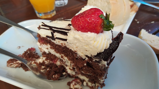 Portion of chocolate cake with cream and strawberries