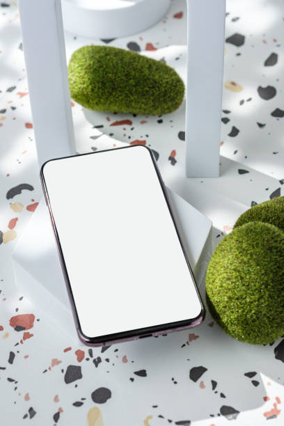 istock mobile phone on white geometric pedestal on terrazzo background with summer sunlight and moss rock 1403752075