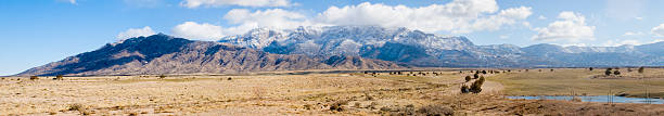 Winter Sandia Mountains panorama True wide panorama of the Sandia Mountains near Albuquerque, New Mexico, in the winter, with snow and ice along the cloudy peaks and a desert golf course in the foreground. bernalillo county stock pictures, royalty-free photos & images