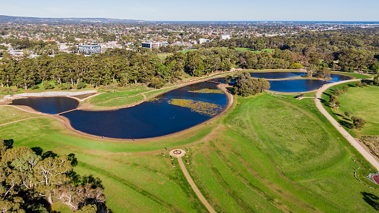 Aerial panoramic view new Brownhill Creek wetlands in Adelaide's Victoria Park (Pakapakanthi) with residential and office buildings in background. Wetlands provide stormwater flood mitigation plus a valuable community recreation area and green space. 16x9 format