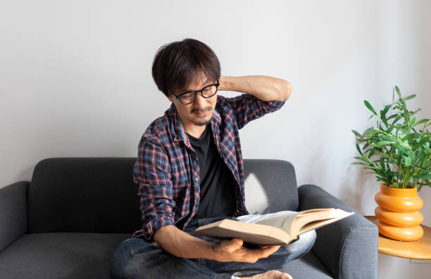 istock Portrait of Asian man rubbing his eyes, tired while reading book. 1403759030
