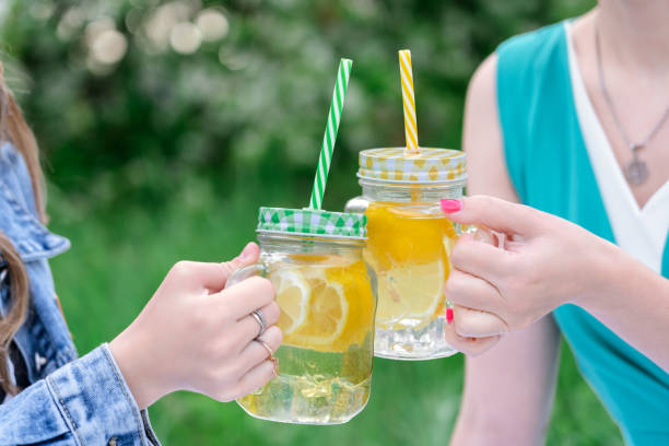 istock Two girls clink cans of lemonade 1403760594