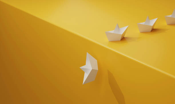 istock Paper boat sails fall a cliff on a yellow background 1403762974