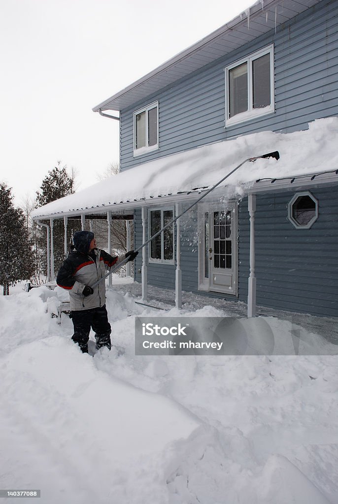 Homme shovelling la neige couvertes de neige du toit - Photo de Hiver libre de droits