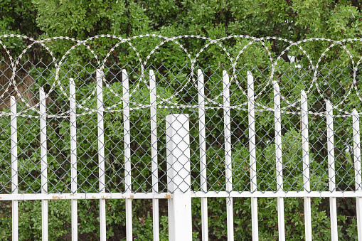 Barbed wire and metal fence at the entrance to prison or military base. Safety and freedom concept
