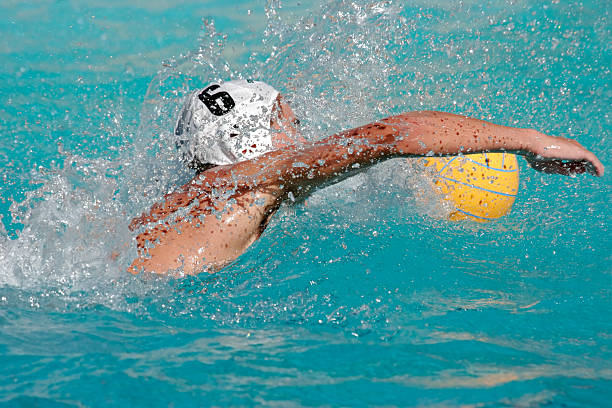 High res photo of a water polo player swimming Water polo player swimming for the ball water polo photos stock pictures, royalty-free photos & images