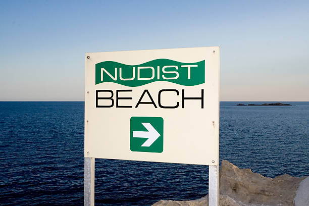 Nudist Beach Sign A sign indicating the direction of a nudist beach with the Adriatic Sea in the backgroung cavtat photos stock pictures, royalty-free photos & images