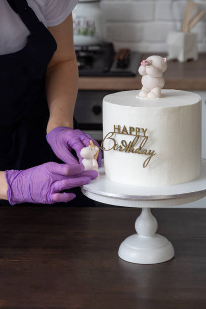 Gloved hands expose chocolate unicorn figurine on substrate with cake for holiday. Selective focus. Photos about confectioners, food, hobbies. stock photo