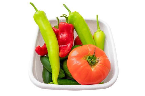Washed vegetables with drops of water in a bowl are waiting for slicing into a salad, isolated on white