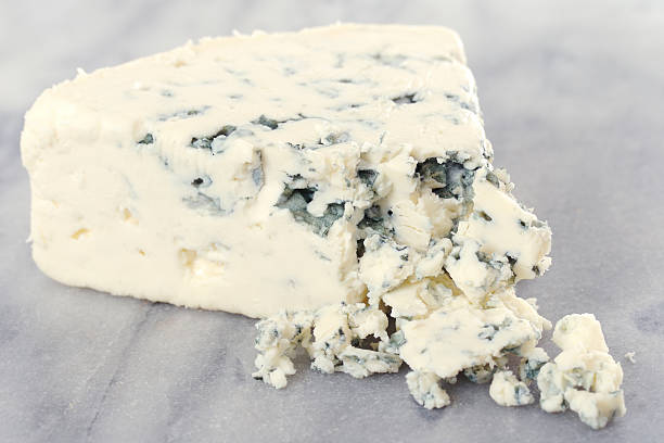 Danish Blue Cheese Partly crumbled Danish blue cheese on a marble cutting table. blue cheese stock pictures, royalty-free photos & images
