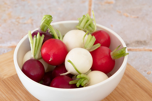 Radishes of different colors in a bowl on a table