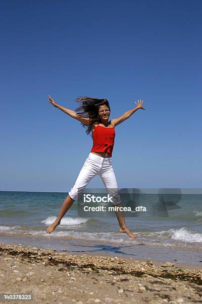 Mujer Salto En La Playa Foto de stock y más banco de imágenes de Adulto - Adulto, Adulto joven, Aire libre