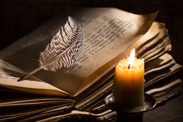 istock Lighting candle near a medieval book. Vintage still life with open old book. 1403792273
