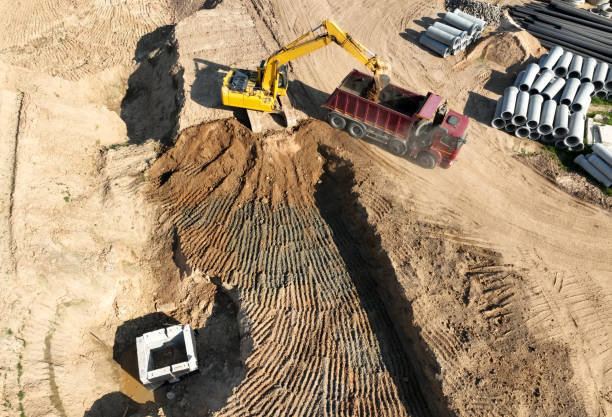 istock Sewage drainage construction. Excavator on earthworks at construction site. Backhoe on earthmoving. Excavator load ground in dump truck. 1403795528