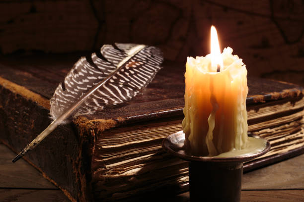 Lighting candle near ancient book. Vintage retro still life style. stock photo