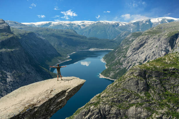 trolltunga rock latem ze stojącym człowiekiem, norwegia. - mountain cliff mountain peak plateau zdjęcia i obrazy z banku zdjęć