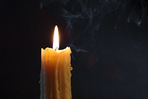 Candle flame burning on black background. Melted wax