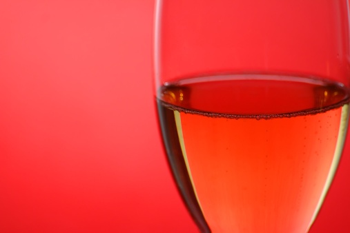 A glass of champagne against a red background.