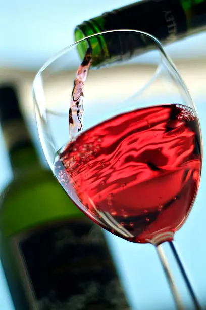 Rose wine being poured into a wine glass from a green bottle