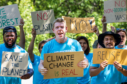 Diversity group of volunteer activist demonstrating in protest for global warming and climate change project with written placard for environmental awareness and reducing plastic consumption