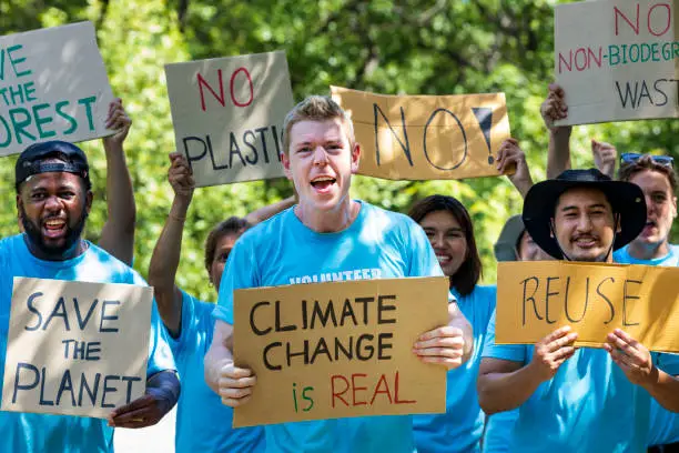 Photo of Diversity group of volunteer activist demonstrating in protest for global warming and climate change project with written placard for environmental awareness and reducing plastic consumption concept