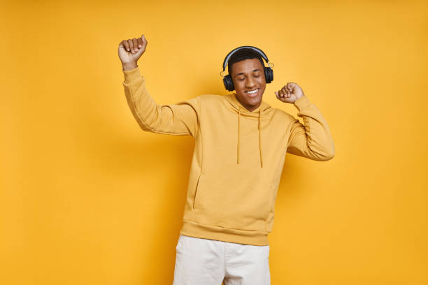 Cheerful mixed race man in headphones dancing stock photo