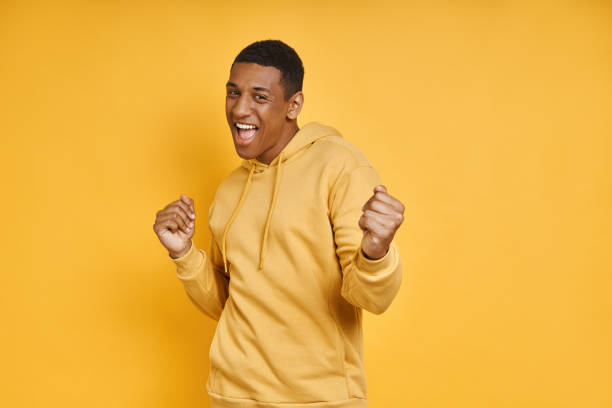 istock Excited mixed race man gesturing while standing against yellow background 1403798857