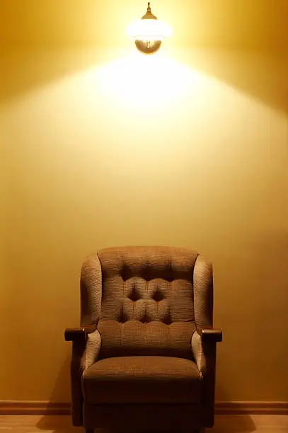 Comfortable brown armchair standing below wall lamp