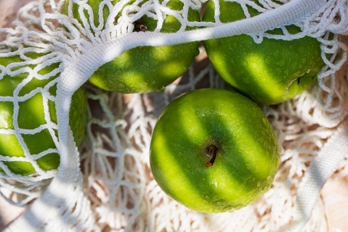 Fresh green apples in a mesh bags, top view.