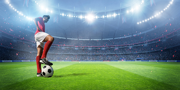 Soccer player's standing in the stadium . Soccer ball's under his foot. An imaginary stadium was modelled and rendered.
