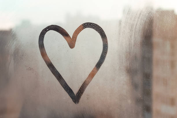 istock Doodle heart painted on glass wet blu window at home 1403804576