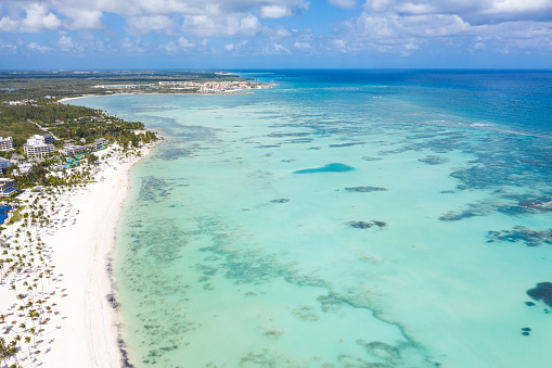 Juanillo beach with palm trees, white sand and turquoise caribbean sea water. Cap Cana is a tourist area in Dominican Republic. Aerial view