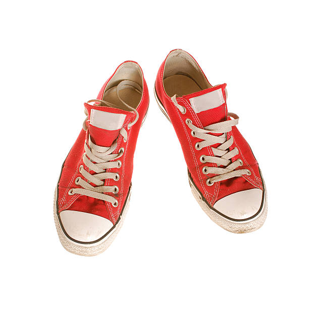 A pair of red canvas shoe hanging on white door