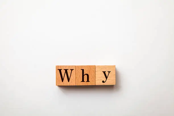 Photo of The character of why. The letters why drawn on a wooden block. Black text.