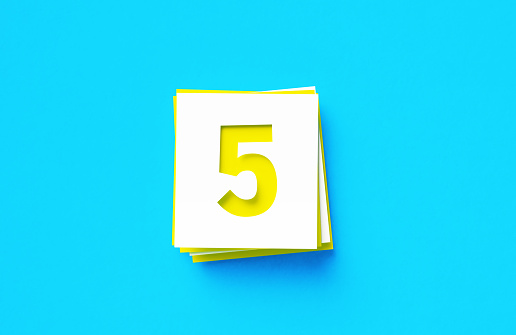 Number 5 written yellow and white adhesive notes sitting on blue background. Horizontal composition with copy space.