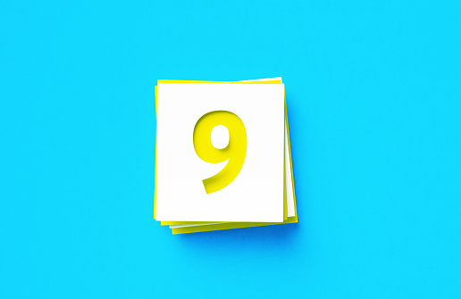 Number 9 written yellow and white adhesive notes sitting on blue background. Horizontal composition with copy space.