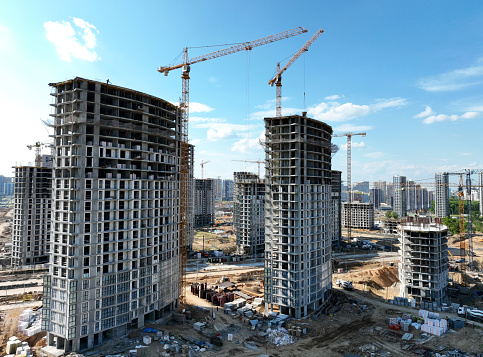 onstruction site with tower cranes on building construction. Builder on formworks. Cranes on pouring concrete in formwork. Tower cranes on construction in built environment. Buildings renovation.\