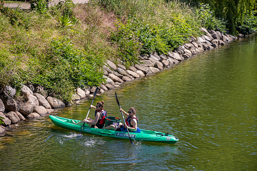 Two young people in a green double kayak collecting garbage in a moat in the center of the Swedish city Malmö