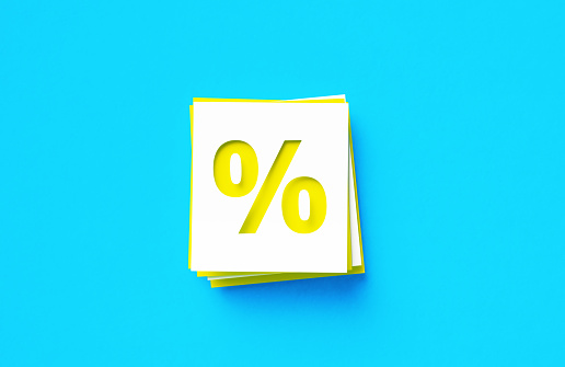 Percentage sign written yellow and white adhesive notes sitting on blue background. Horizontal composition with copy space.