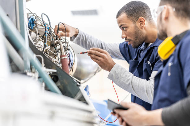 Aircraft mechanics examining helicopter engine with multimeter, using multimeter, side view stock photo