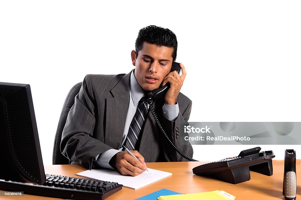 Hispanic Business Man Handsome young business man in a grey suit at his desk talking on the telephone Mexican Culture Stock Photo