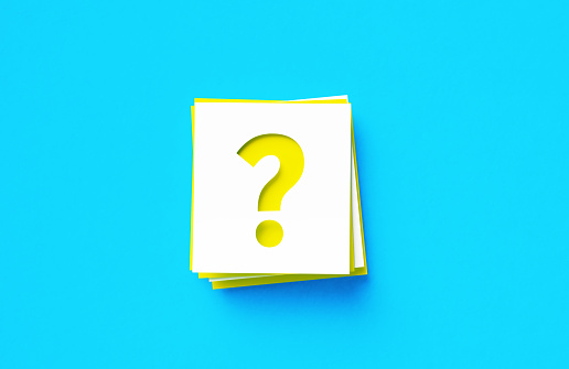 Question mark written yellow and white adhesive notes sitting on blue background. Horizontal composition with copy space.