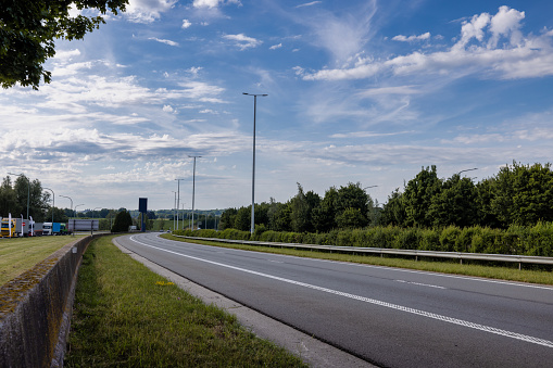 Empty road in green nature from low angle with blue dramatic sky and clouds in the background. Idea for composite or sky replacement.\nCopy space provided.