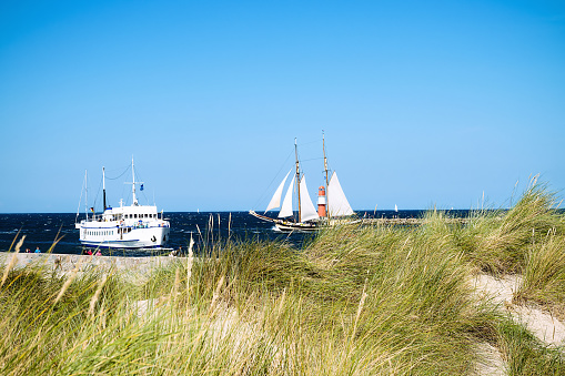 Ships at the harbor entrance from the baltic sea to warnemuende and rostock with promenade, lighthouse and dunes.