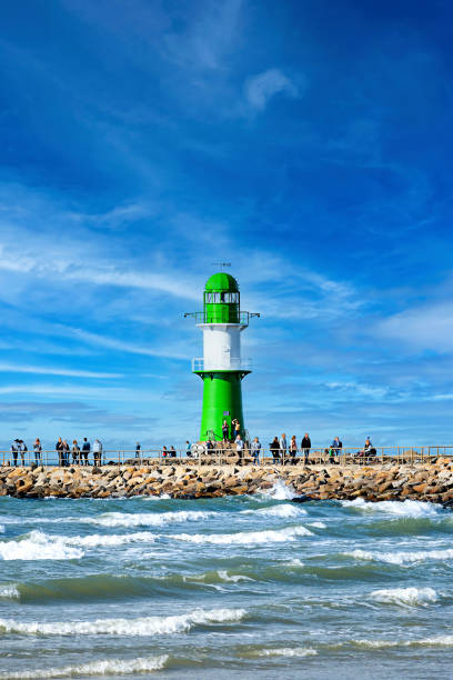 Lighthouse of Warnemuende and Rostock with tourists on the promenade. stock photo