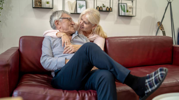 istock Woman embracing husband sitting on the couch 1403815855