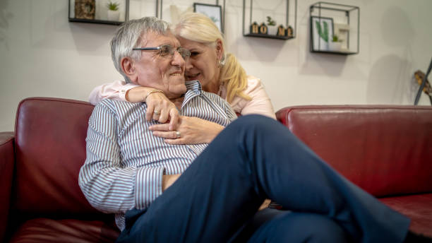 istock Woman embracing husband sitting on the couch 1403816011